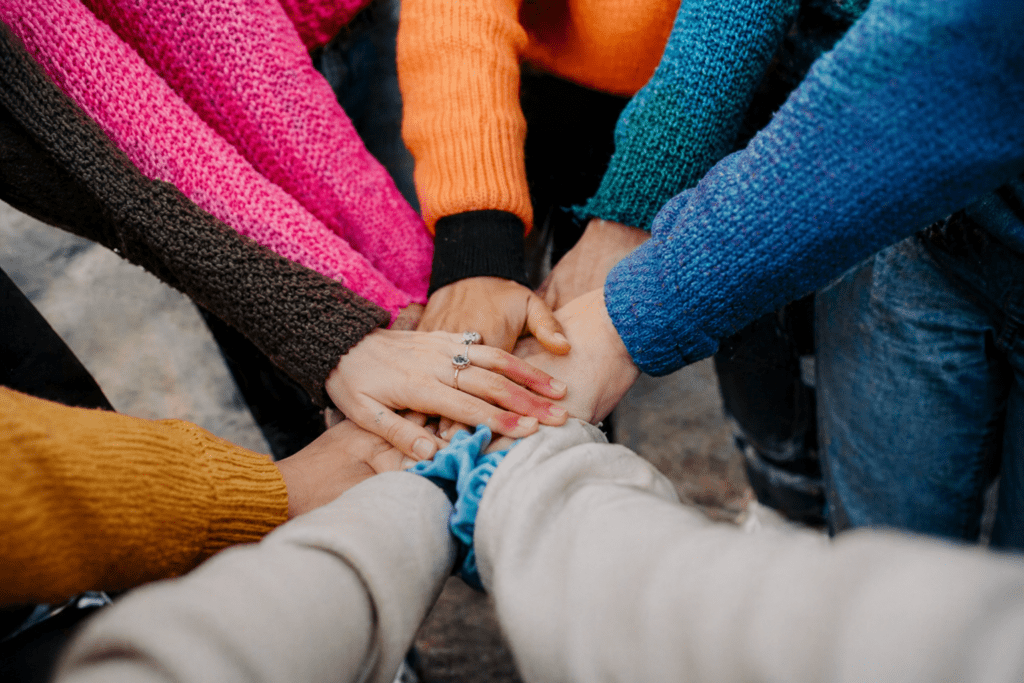 Diverse groep mensen steekt handen samen als teken van eenheid en samenwerking