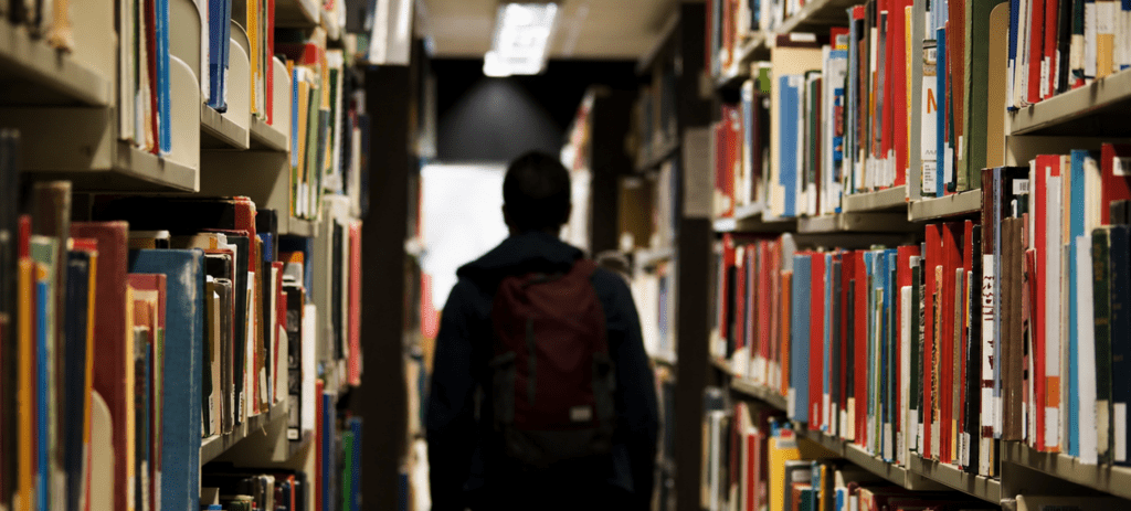 Silhouet van een student tussen boekenrekken in een bibliotheek