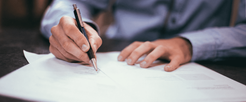 Close-up van een hand die een officieel document ondertekent met een pen