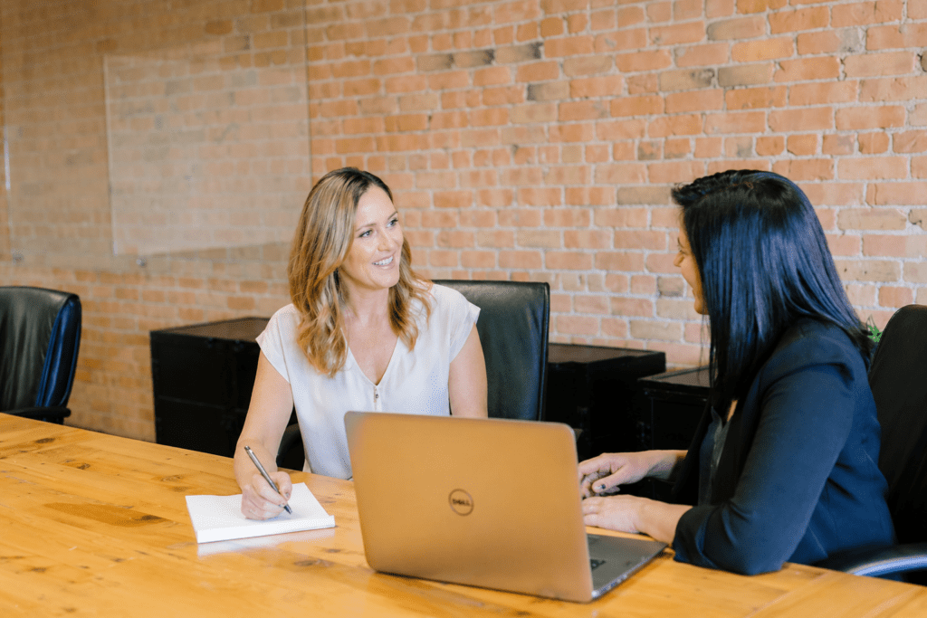 Twee vrouwen voeren een professioneel gesprek aan een vergadertafel met laptop